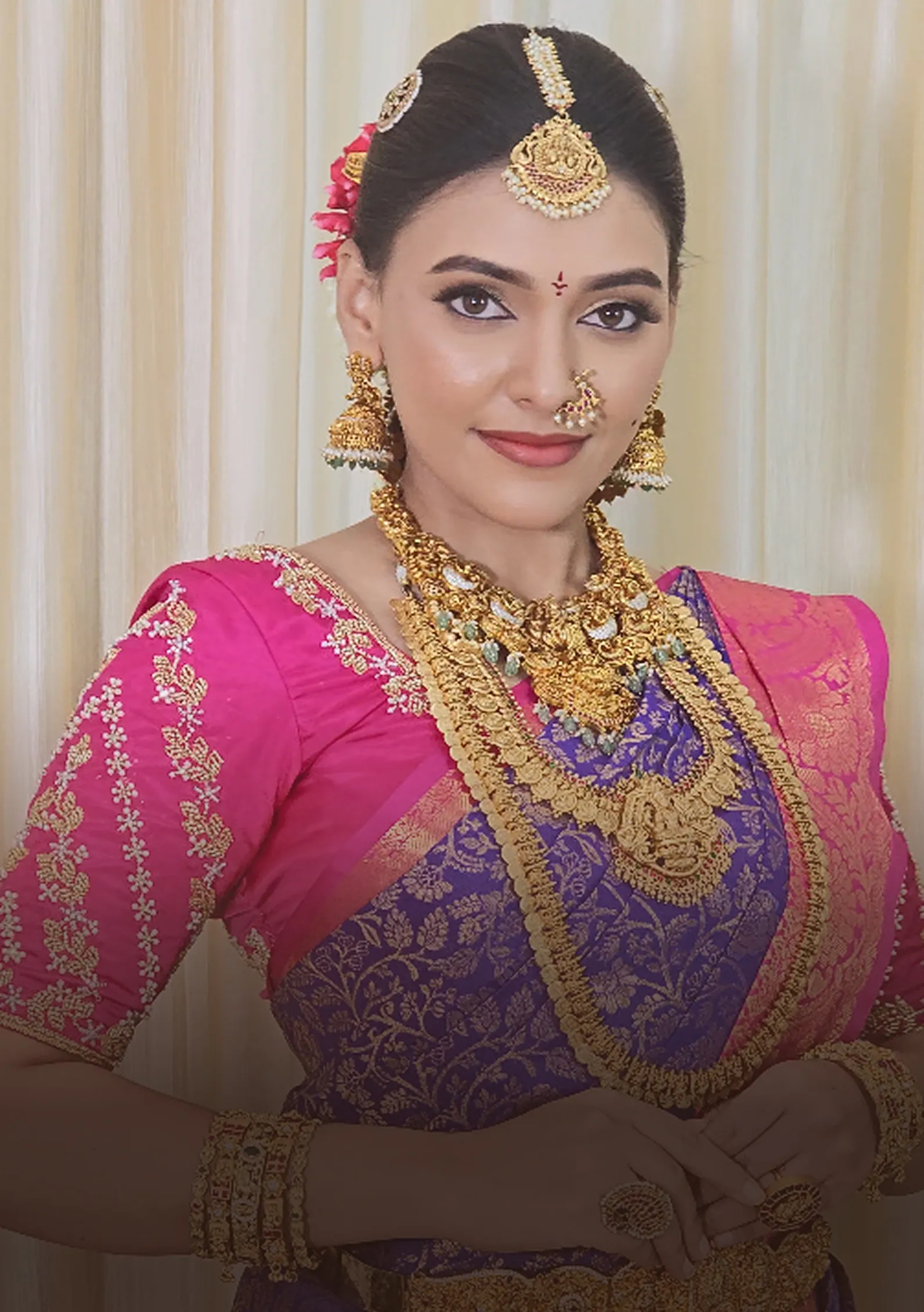 Bride in a pink and purple saree with layered temple jewellery