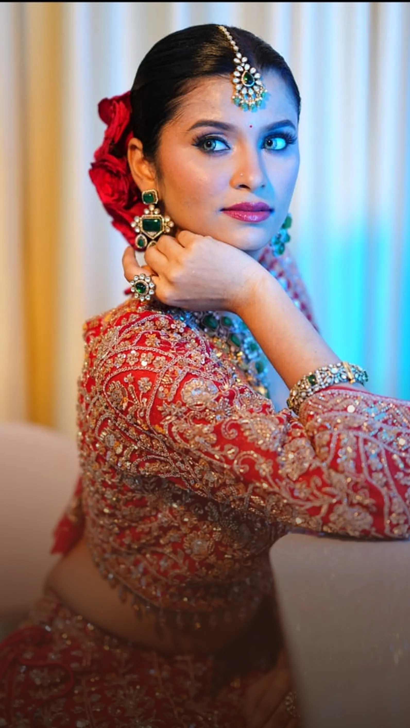 Bride in a red embroidered lehenga resting on a sofa
