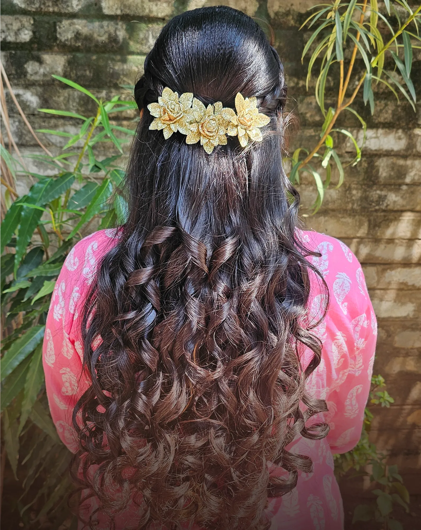 Long curls finished with a floral hair clip, seen from behind