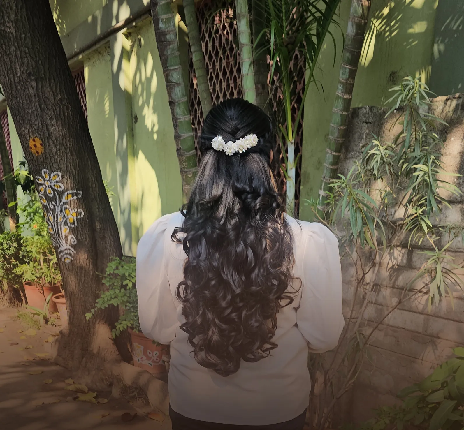 Half-up hairstyle with long curls and a pearl clip